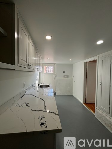 A kitchen with a marble countertop and white cabinets.