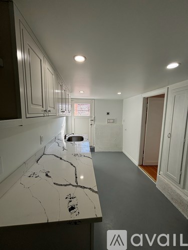 A kitchen with a marble countertop and white cabinets.