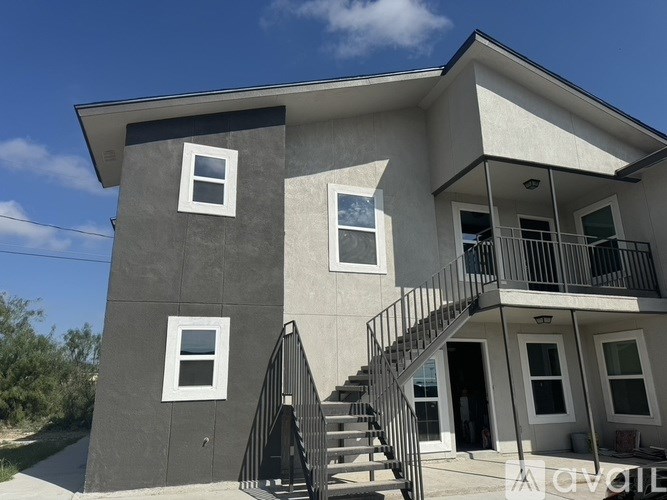 A modern house with a grey and white exterior and a black metal staircase.