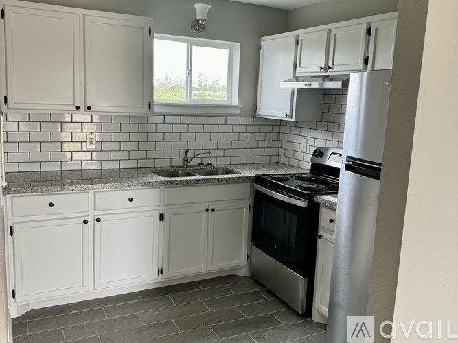 A kitchen with white cabinets and a tiled backsplash.