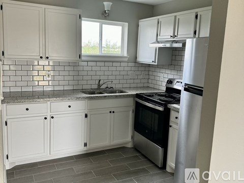 A kitchen with white cabinets and a tiled backsplash.