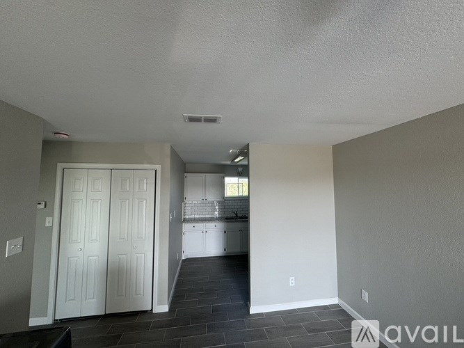 A kitchen with white cabinets and a black floor leading to a hallway.