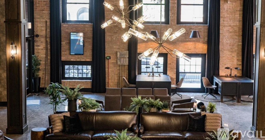 A living room with a brown leather couch and a chandelier.
