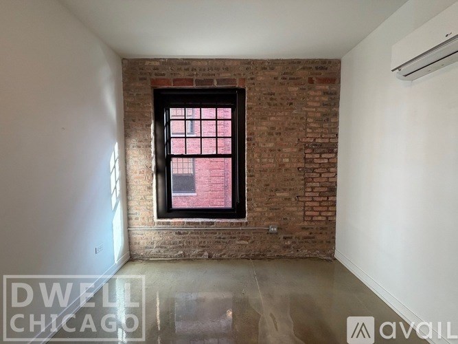 A room with a brick wall and a window showing a red building outside.