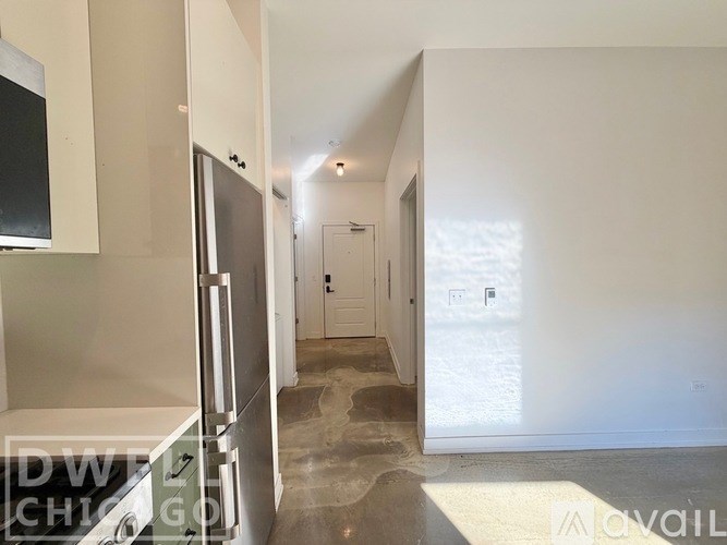 A hallway with a refrigerator on the left and a door at the end.