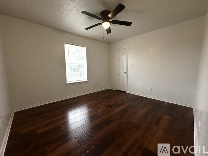 A room with a ceiling fan and wooden flooring.