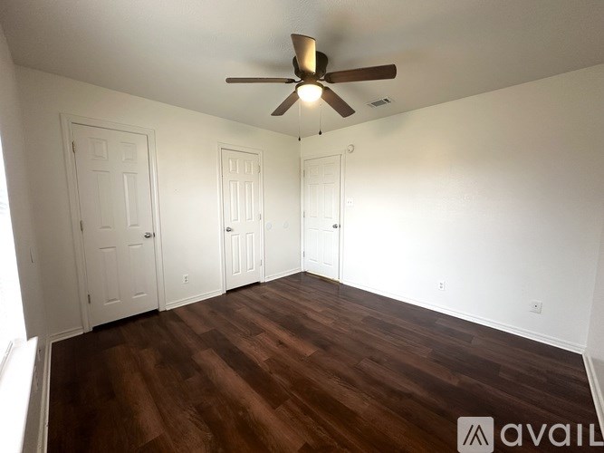 A room with a ceiling fan and wooden flooring.