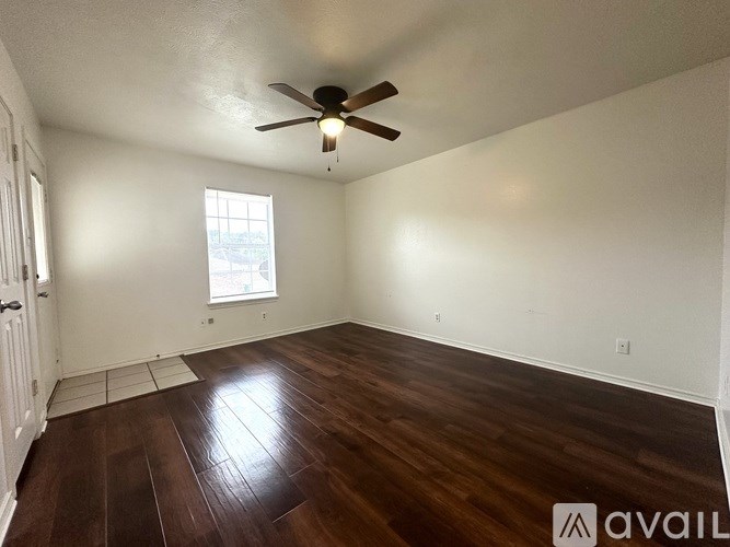 A room with a ceiling fan and wooden flooring.