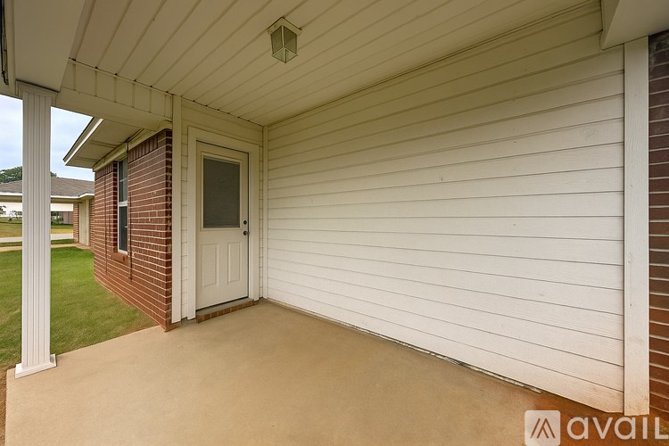A white covered porch with a door and a window.