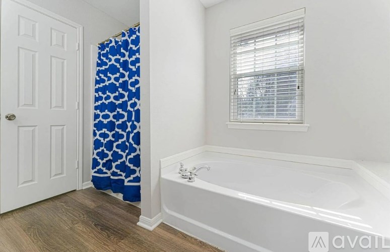 A white bathroom with a blue shower curtain.