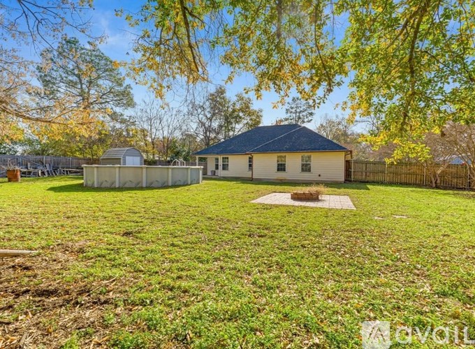 A house with a black roof is surrounded by a grassy area with trees.