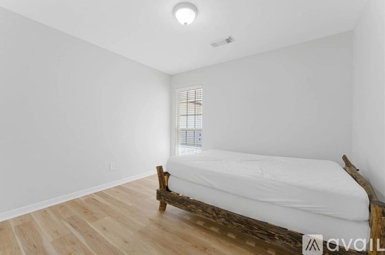A bedroom with a bed and wooden flooring.