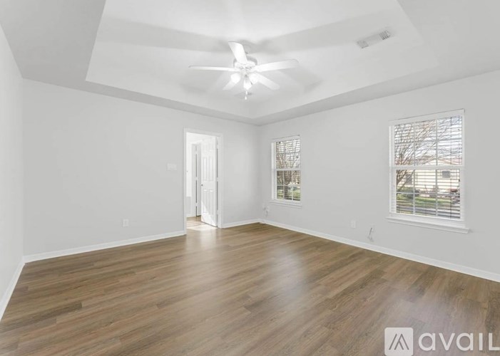 A spacious room with wooden flooring and a ceiling fan.