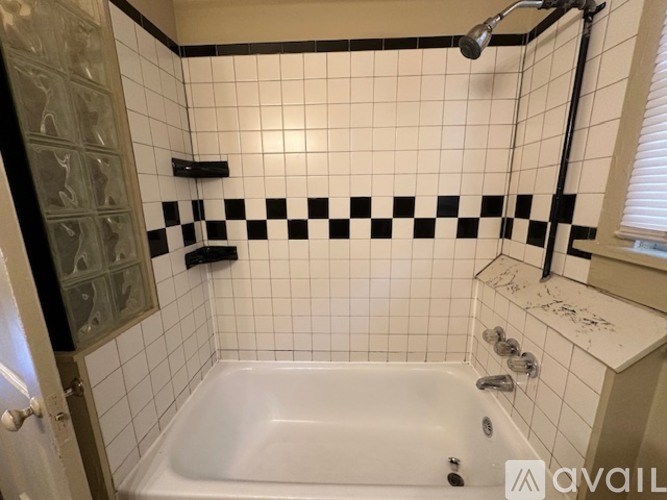 A white bathtub with black and white tiles on the wall.