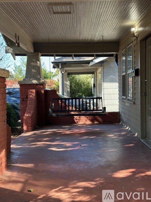 A porch with a brick pillar and a black railing.