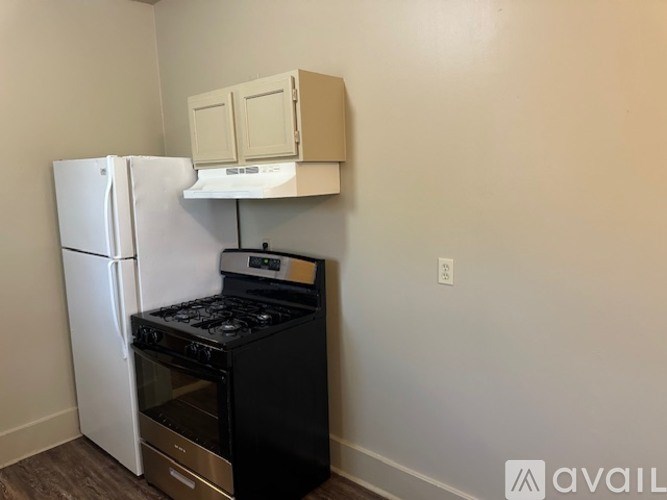 A kitchen with a white fridge and black stove top oven.