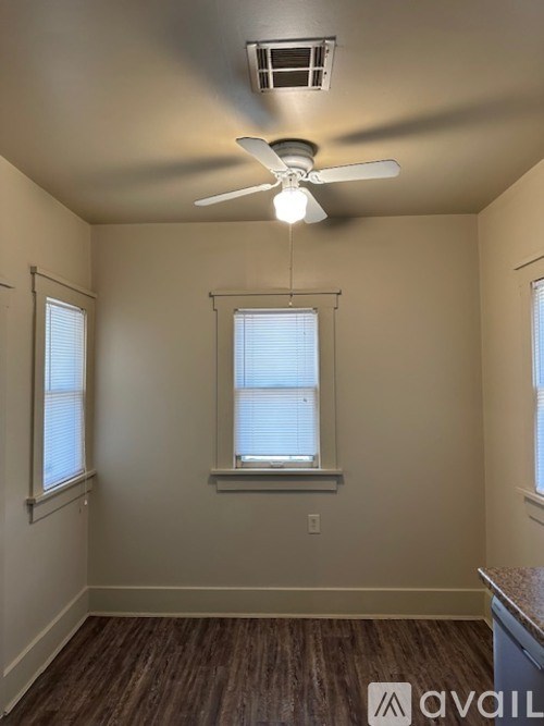 A room with a ceiling fan and two windows.