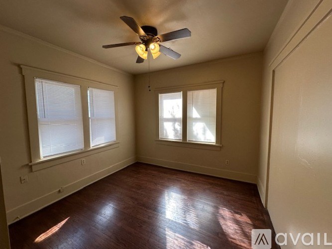 A room with a ceiling fan and three windows.