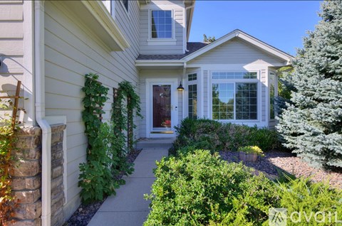 A house with a white door and windows surrounded by green plants.