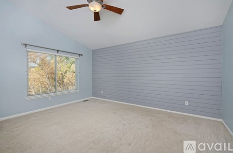 A room with a ceiling fan and a window with blinds.
