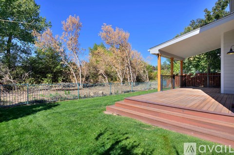 A backyard with a wooden deck and a house.