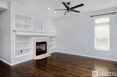 A living room with a fireplace and a fan.