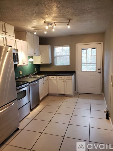 A kitchen with white cabinets and a stainless steel refrigerator.