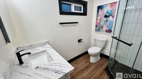 A bathroom with a toilet, sink, and a glass shower door.