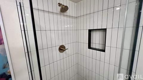 A white tiled shower with a black frame on the door.