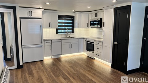 A modern kitchen with white cabinets and a wooden floor.