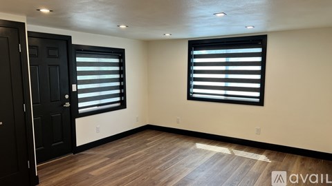 A room with a black door and window with blinds.