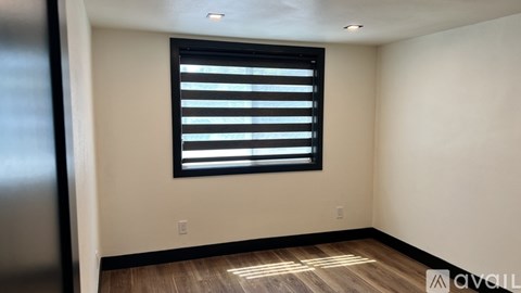 A room with a window covered by black horizontal blinds.