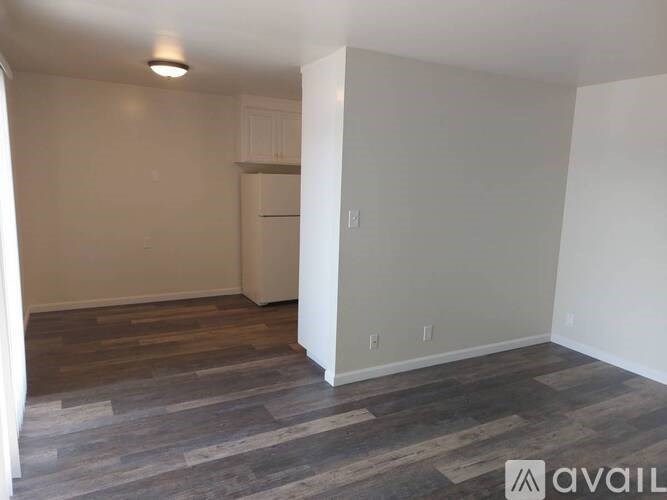 A room with wooden flooring and white walls is available for rent.