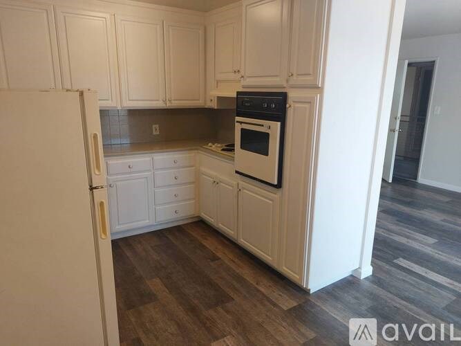 A kitchen with white cabinets and a white refrigerator.