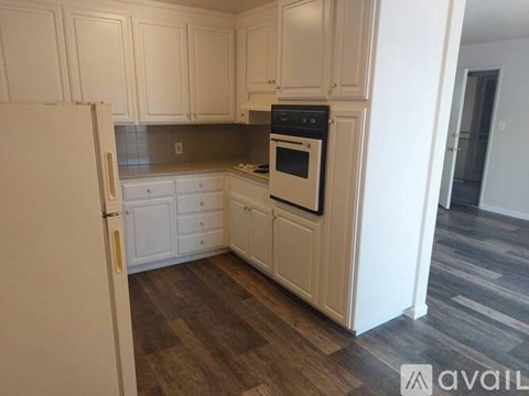 A kitchen with white cabinets and a white refrigerator.