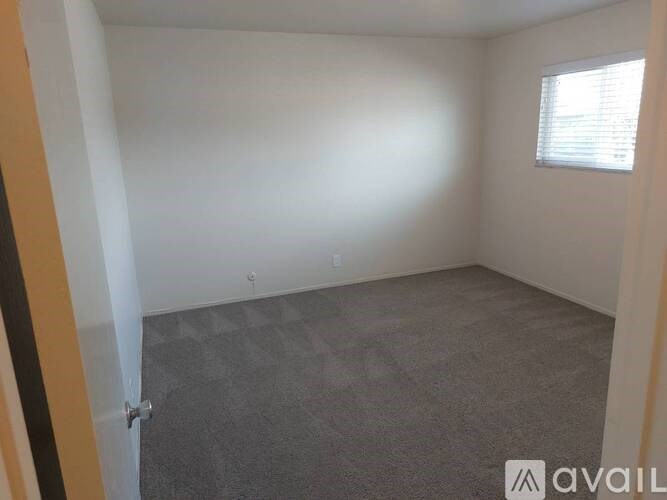 A room with a carpeted floor and a window with blinds.