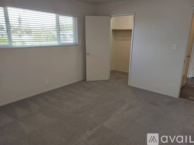 A room with a carpeted floor and a window with blinds.