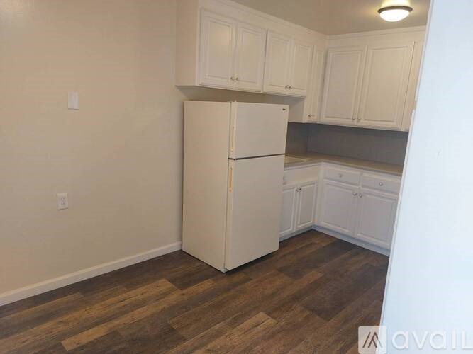 A kitchen with a white refrigerator and wooden floors.