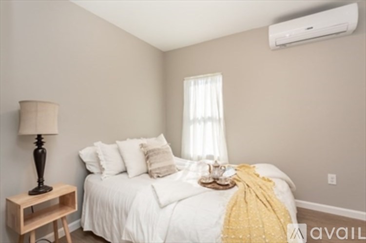 A bedroom with a bed, nightstand, lamp, and window.