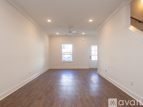 A spacious room with wooden floors and two windows.