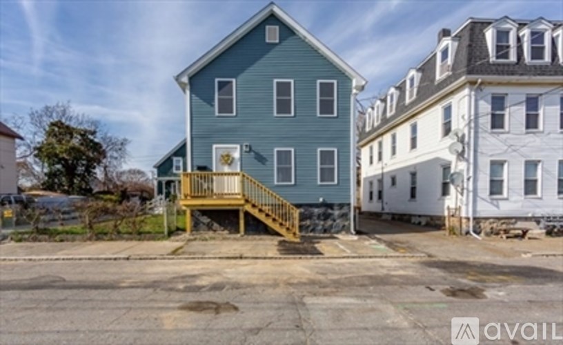 A blue house with a porch and a white house in the background.