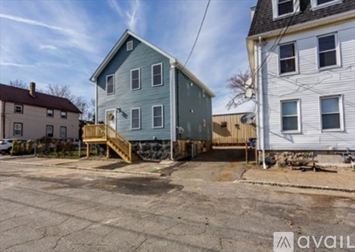 A blue house with a porch and a white house in the background.
