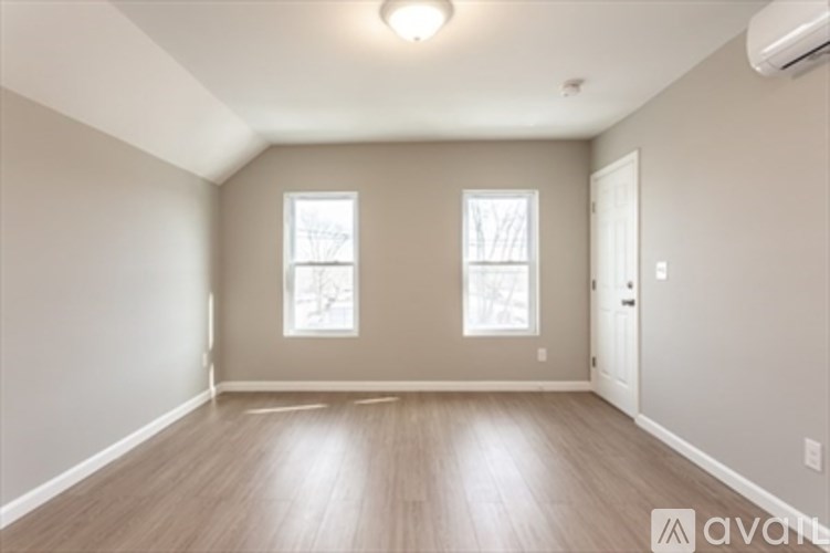 A room with wooden floors and two windows.