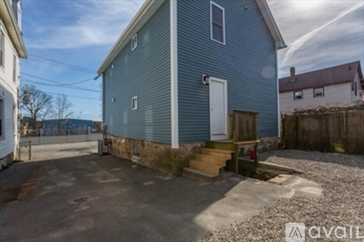 A blue house with a white door and a gravel driveway.