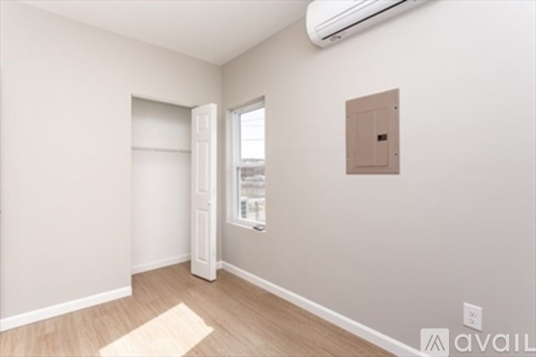 A room with a door, window, and a wall-mounted air conditioner unit.
