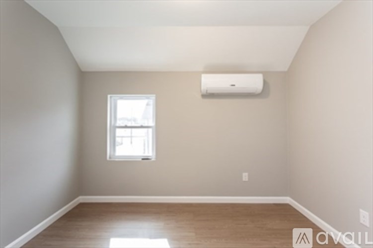 A room with a window and an air conditioner on the wall.