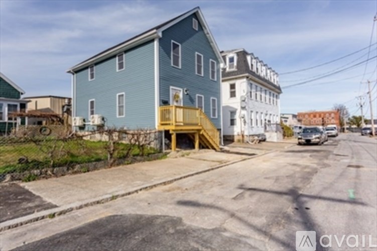 A blue house with a wooden staircase leading to the front door.