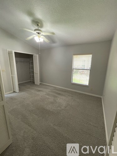 A room with a carpet floor, a ceiling fan, and a window with blinds.