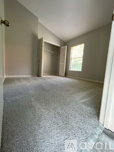 A carpeted room with a door open to another room.