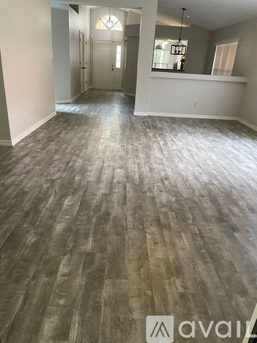 A room with wooden flooring and a doorway leading to another room.